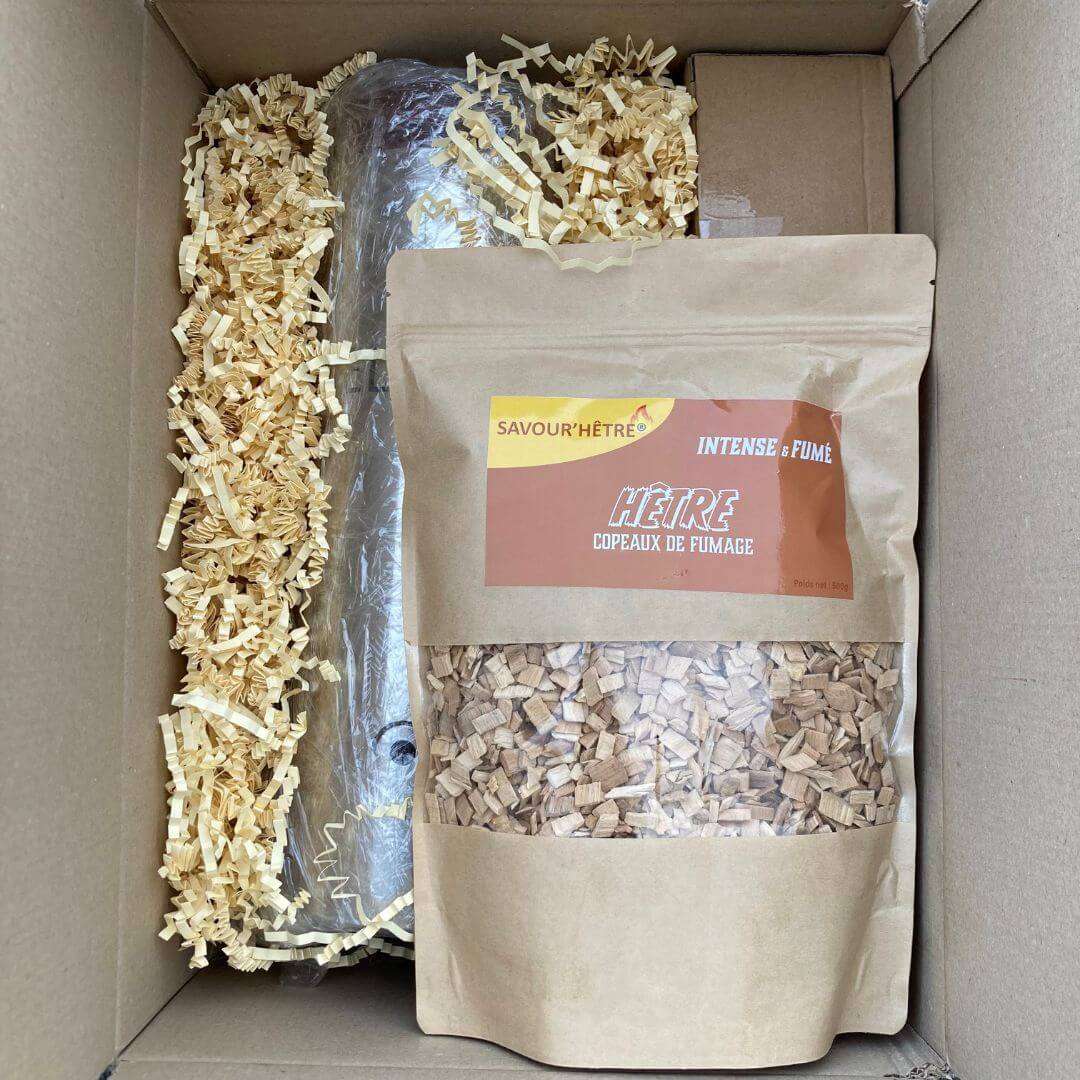 Carton d'emballage pour le générateur de fumée froide Delismo. Contient : un générateur électrique, 1 kilogramme de copeaux de fumage de hêtre, une pompe à air et un briquet tourche, le tout joliment emballé avec de la frisure de papier